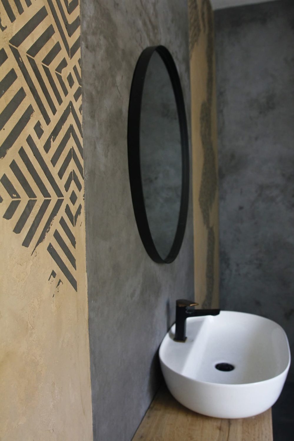Baño en microcemento con lavabo redondo blanco y grifería negra