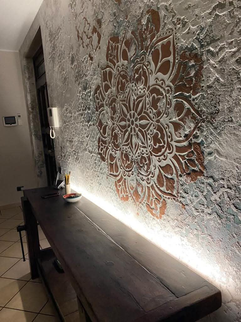 Recibidor con pared decorada en microcemento, banco de madera e iluminación cálida